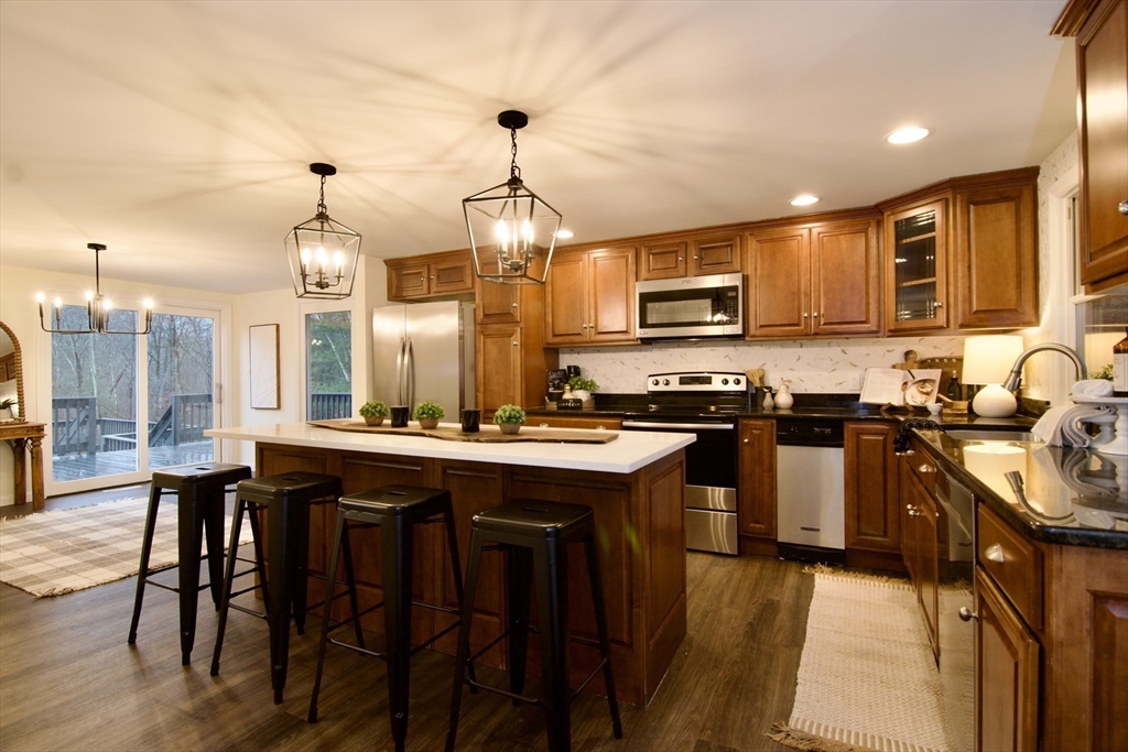 12 Rose Circle Hampden, MA 01036 - Photo 14 of 41 a kitchen with stainless steel appliances granite countertop a stove top oven a sink dishwasher a dining table and chairs with wooden floor