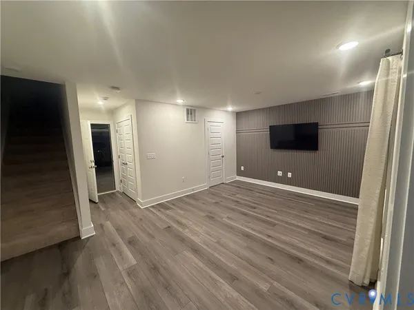 an empty room with wooden floor and bathroom view
