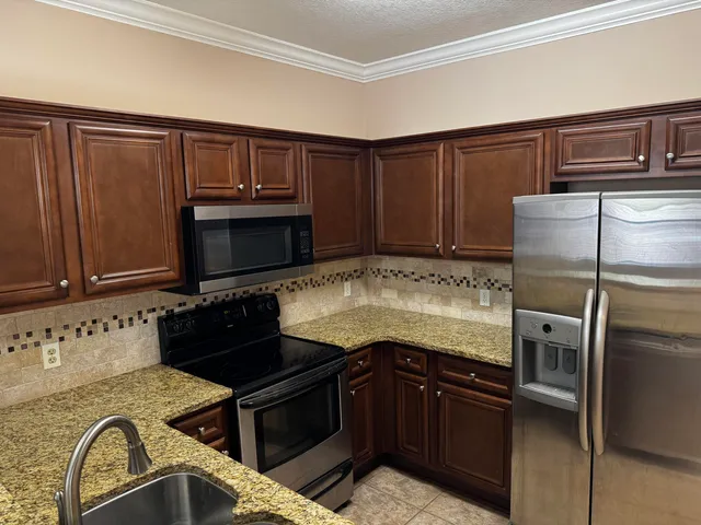 a kitchen with granite countertop a refrigerator stove and sink