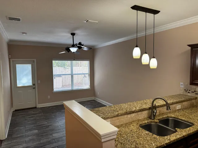 a kitchen with a sink chandelier and living room view