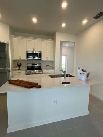 a living room with stainless steel appliances kitchen island granite countertop a sink and cabinets