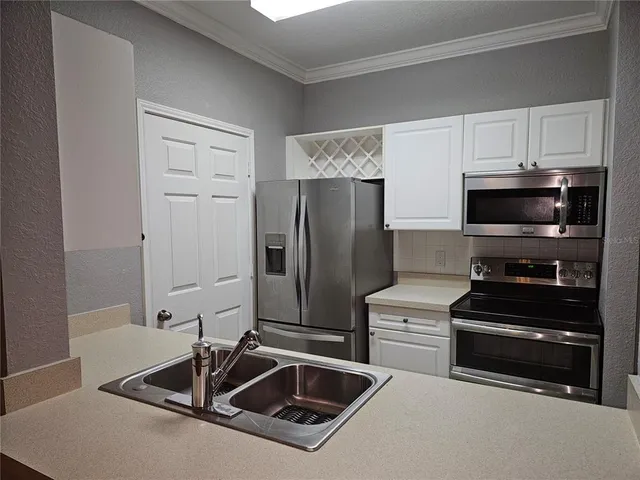 a kitchen with a sink a microwave a refrigerator and cabinets