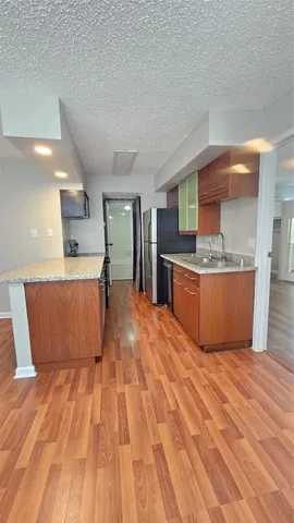 a room with kitchen island stainless steel appliances wooden floor and view living room