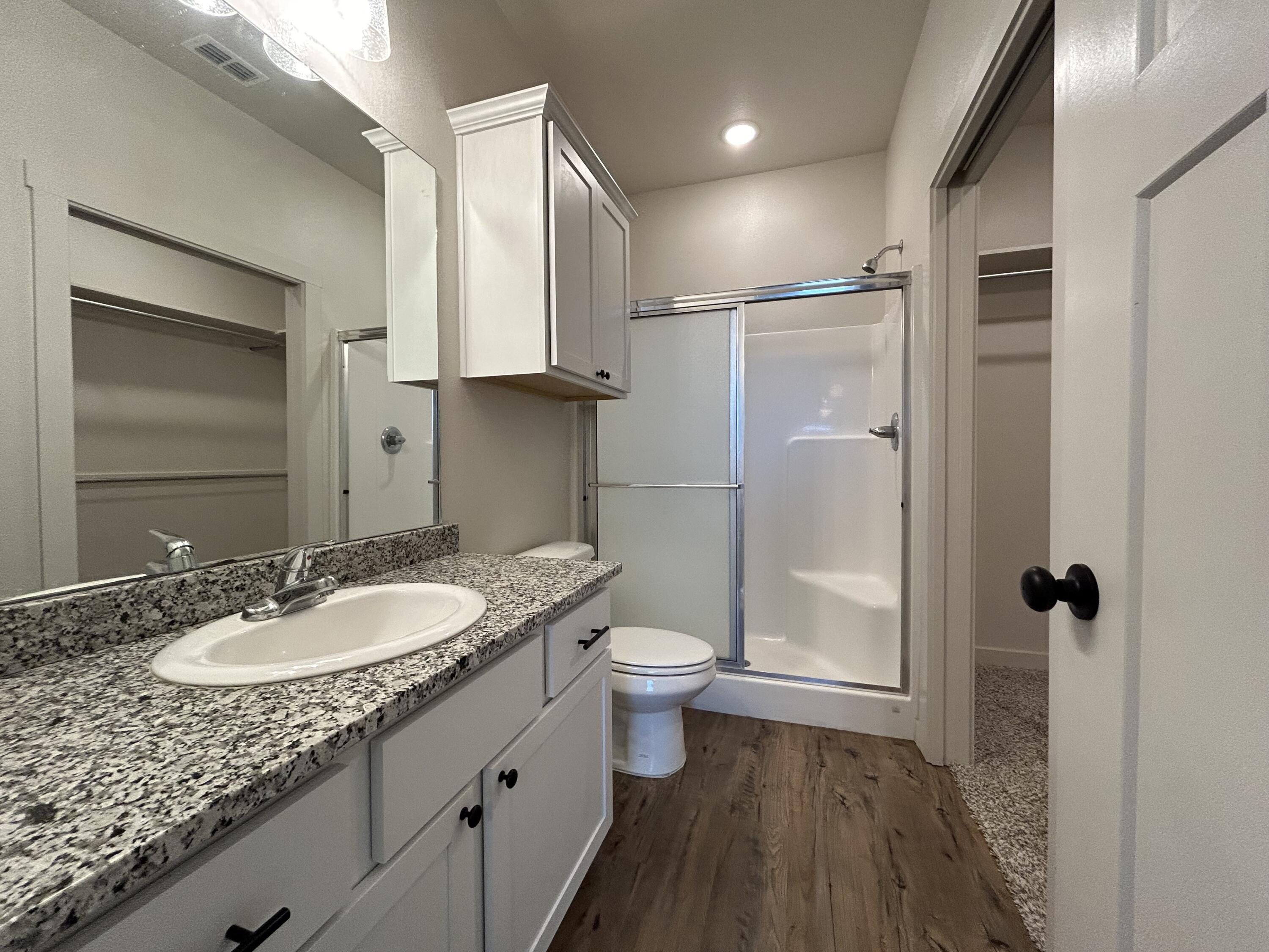 2547 138th Street Lubbock, TX 79423 - Photo 7 of 11 a bathroom with a granite countertop sink toilet a mirror a shower and vanity