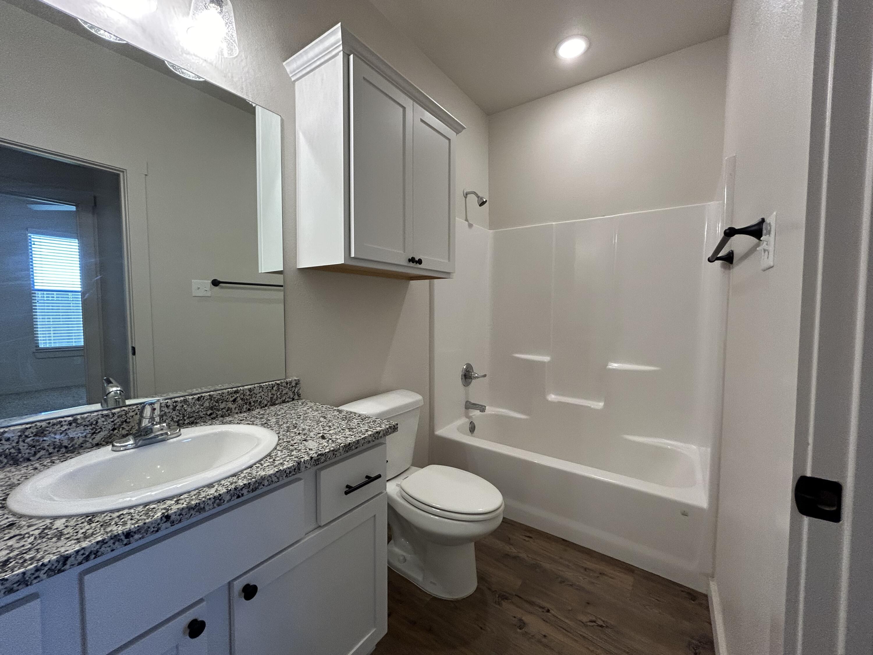 2547 138th Street Lubbock, TX 79423 - Photo 10 of 11 a bathroom with a granite countertop sink toilet a mirror and shower