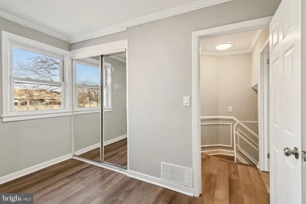 a view of an empty room with window and wooden floor