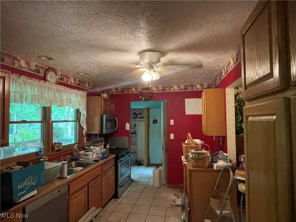 9439 Williams Road Diamond, OH 44412 - Photo 11 of 18 Kitchen with stainless steel appliances, a ceiling fan, light tile patterned flooring, a textured ceiling, and a sink