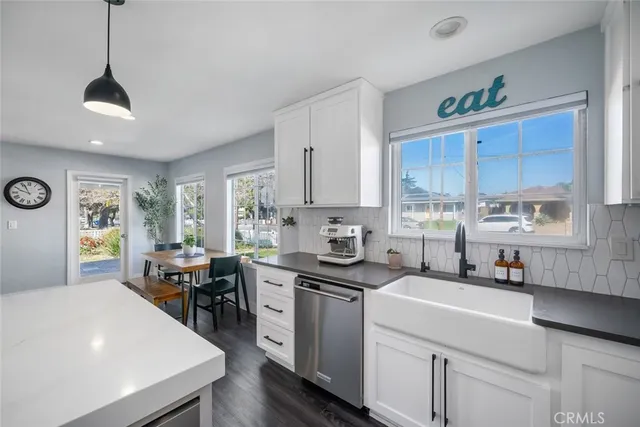 a kitchen with stainless steel appliances a dining table chairs stove refrigerator and cabinets