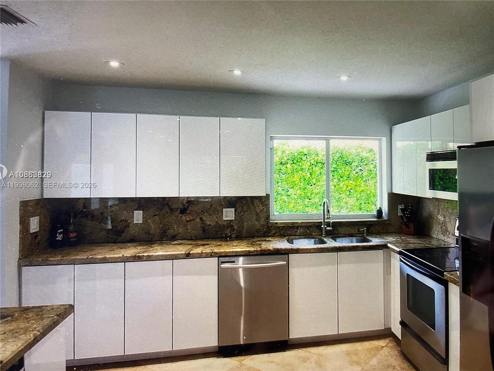 10900 Southwest 107th Avenue Miami, FL 33176 - Photo 6 of 26 a kitchen with granite countertop a sink a counter top space appliances and cabinets