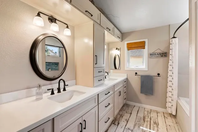 a bathroom with a double vanity sink mirror and bathtub