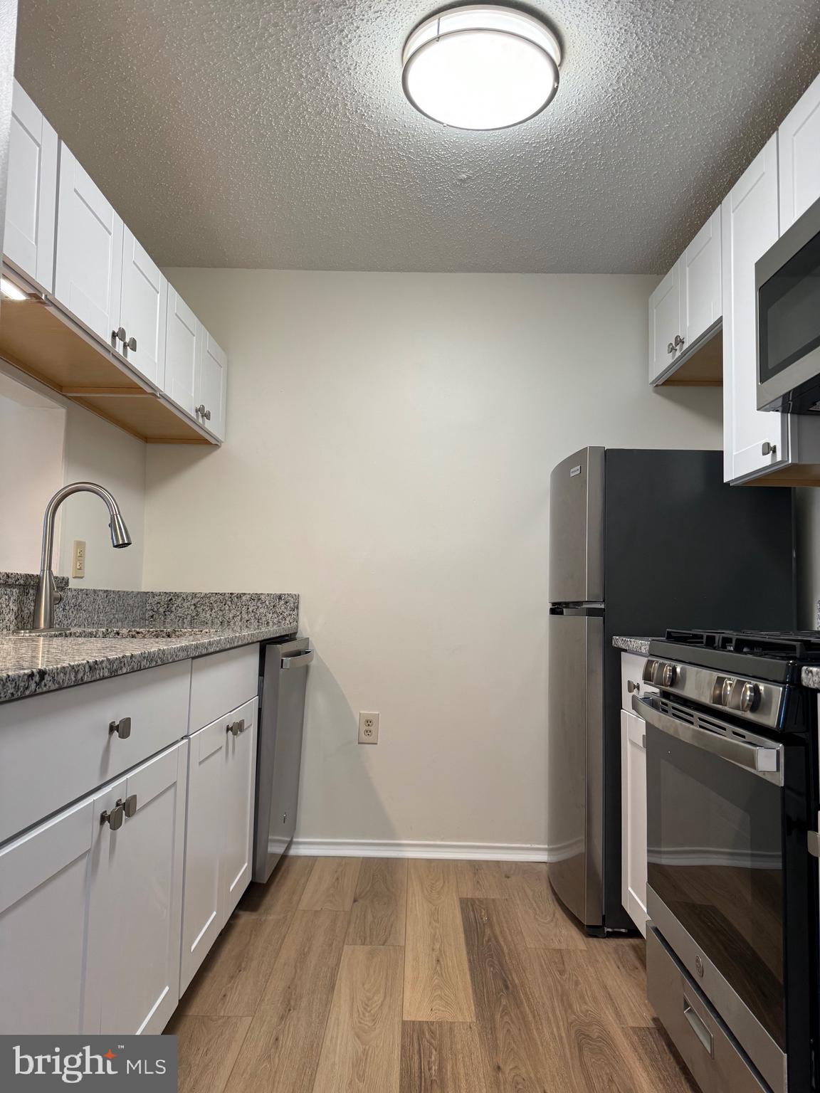 20952 Timber Ridge Terrace, Unit 301 Ashburn, VA 20147 - Photo 6 of 14 a kitchen with granite countertop a stove a sink and a microwave