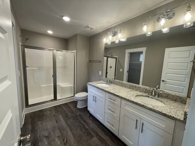 a spacious bathroom with a granite countertop sink a toilet a mirror and shower