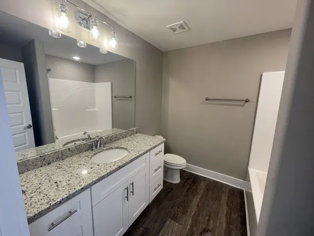 a bathroom with a granite countertop sink a toilet and a mirror