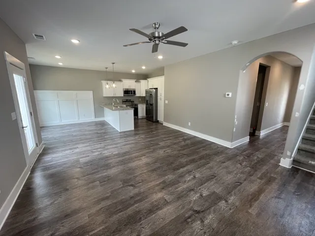 an empty room with wooden floor and a ceiling fan