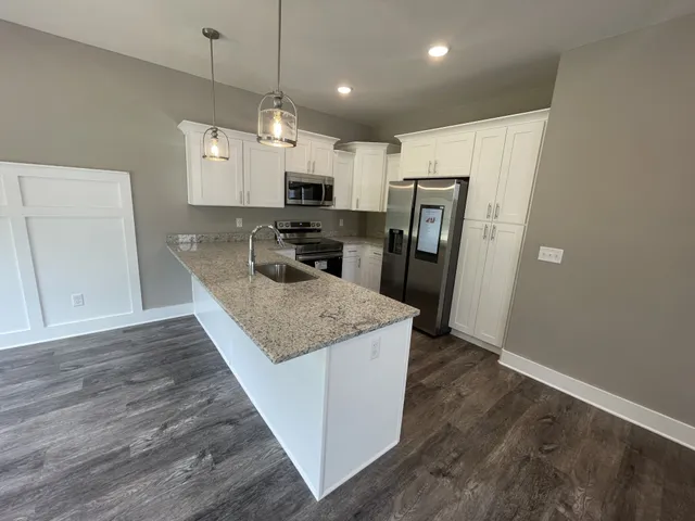 a kitchen with stainless steel appliances granite countertop a refrigerator a stove top oven a sink and dishwasher