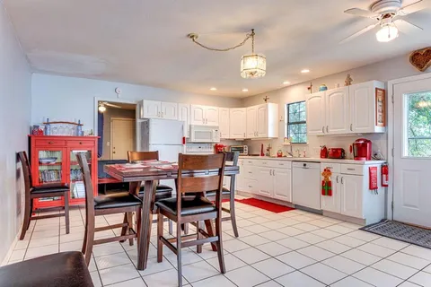 a kitchen with stainless steel appliances kitchen island granite countertop a table chairs and a refrigerator
