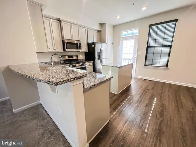 a kitchen with stainless steel appliances granite countertop a sink stove microwave and refrigerator