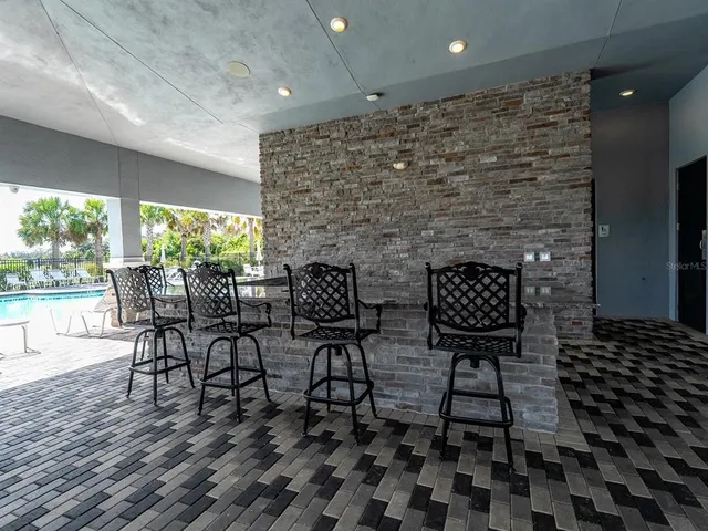 a view of a swimming pool with lawn chairs plants and large tree