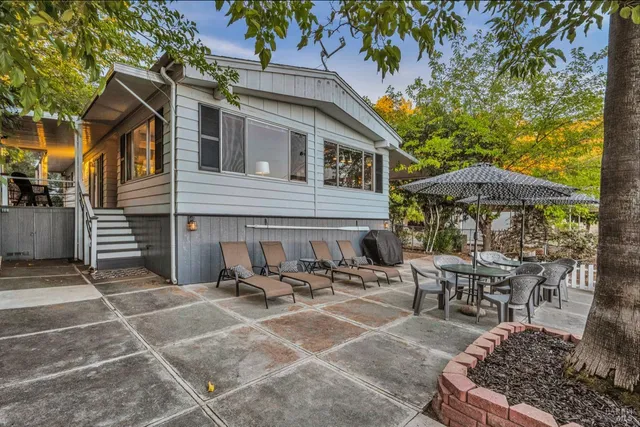 a view of a patio with table and chairs under an umbrella with a barbeque