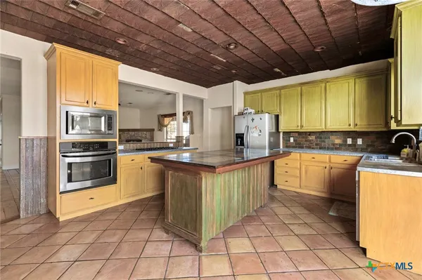a kitchen with granite countertop a sink a counter top space appliances and cabinets