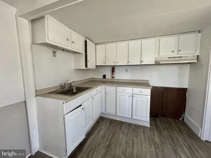 a kitchen with cabinets stainless steel appliances a sink and wooden floor