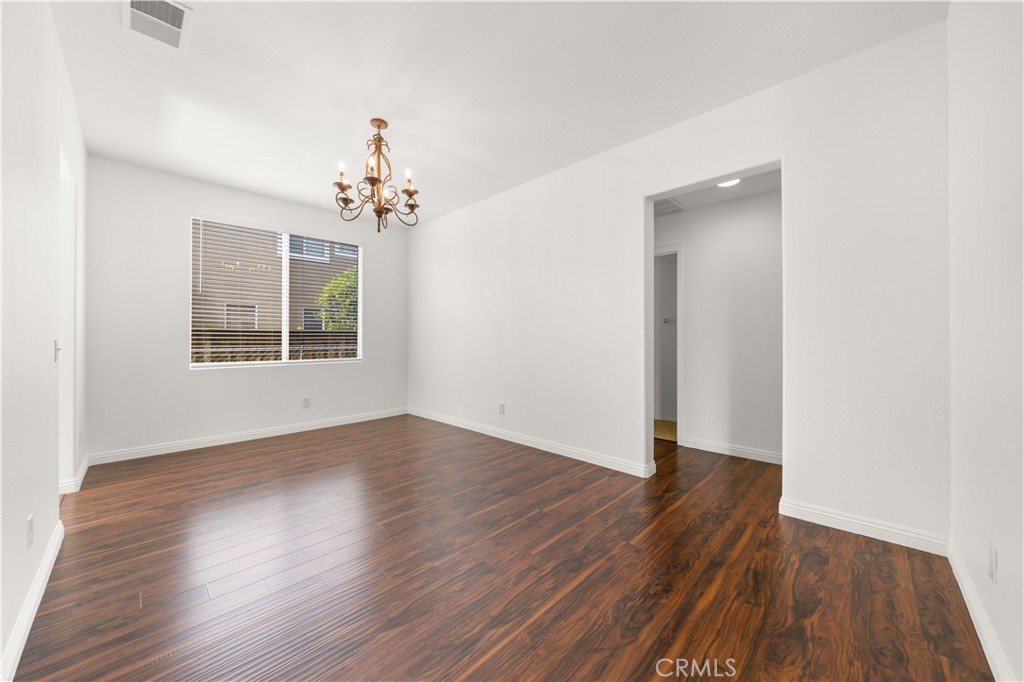 8679 Cabin Place Riverside, CA 92508 - Photo 19 of 35 an empty room with wooden floor chandelier and windows