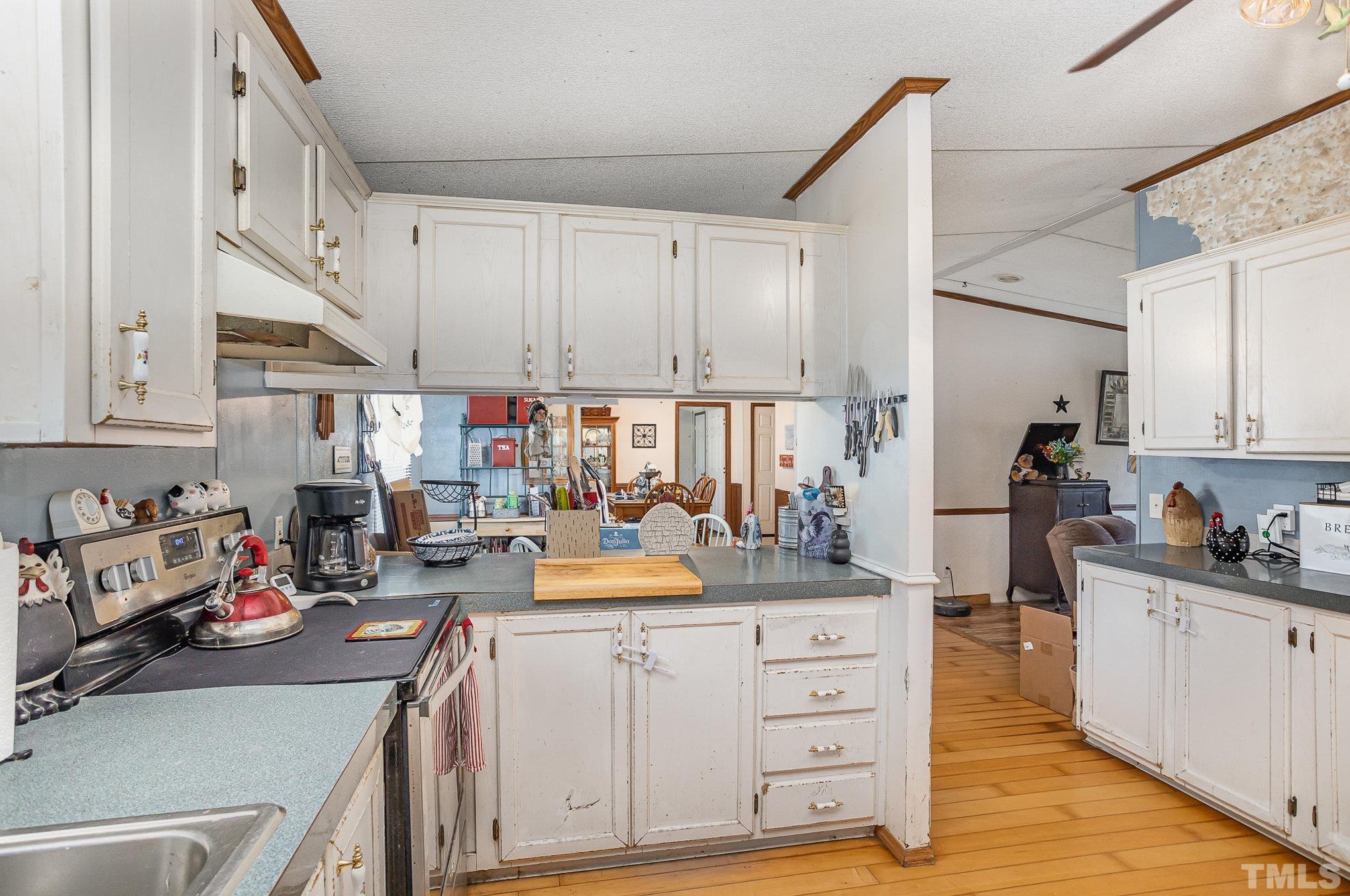 6301 Sandy Creek Road Stedman, NC 28391 - Photo 14 of 27 a kitchen with a sink dishwasher stove and white cabinets with wooden floor