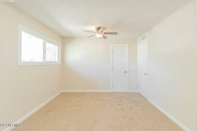 an empty room with a window and a ceiling fan