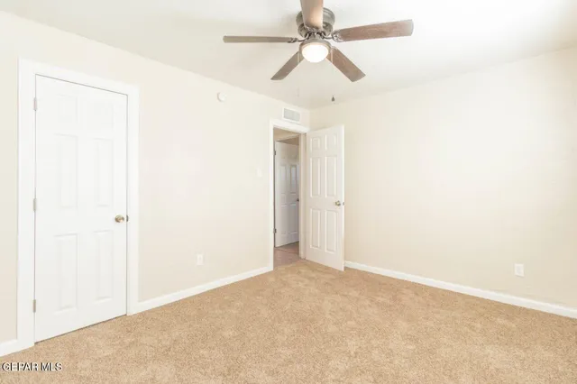 an empty room with a ceiling fan and a window