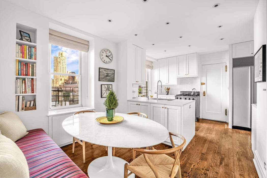 215 East 72nd Street, Unit 10W Manhattan, NY 10021 - Photo 5 of 14 a kitchen with a table chairs refrigerator and window