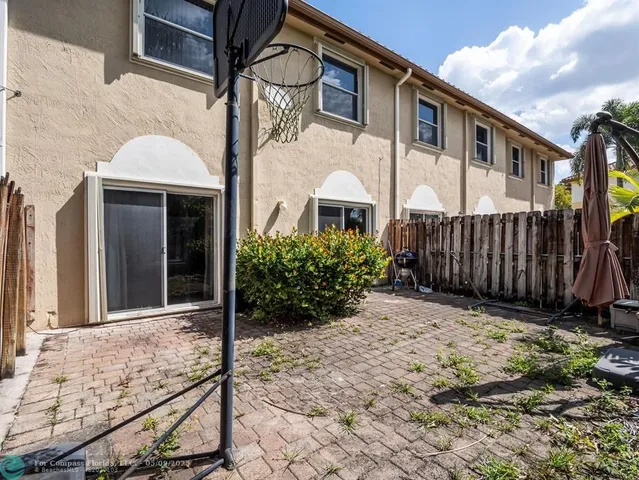 a view of a white house with many windows next to a yard