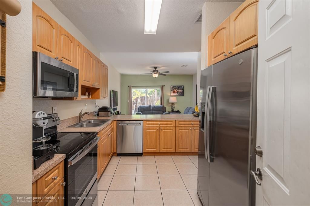 5048 Southwest 136th Avenue Miramar, FL 33027 - Photo 6 of 49 a kitchen with stainless steel appliances granite countertop a refrigerator a stove top oven a sink dishwasher and wooden cabinets