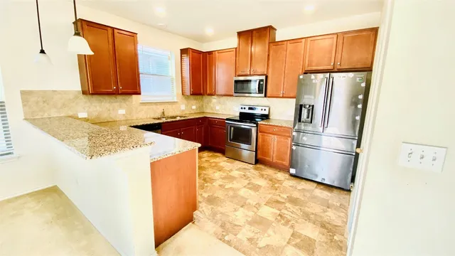 a kitchen with stainless steel appliances granite countertop a refrigerator a stove a sink and a refrigerator