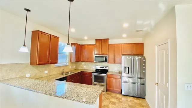 a kitchen with stainless steel appliances granite countertop a refrigerator a stove a sink and a microwave