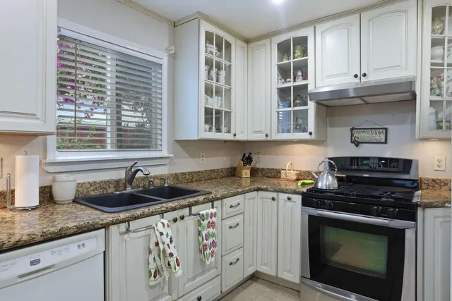 a kitchen with granite countertop a stove sink and cabinets