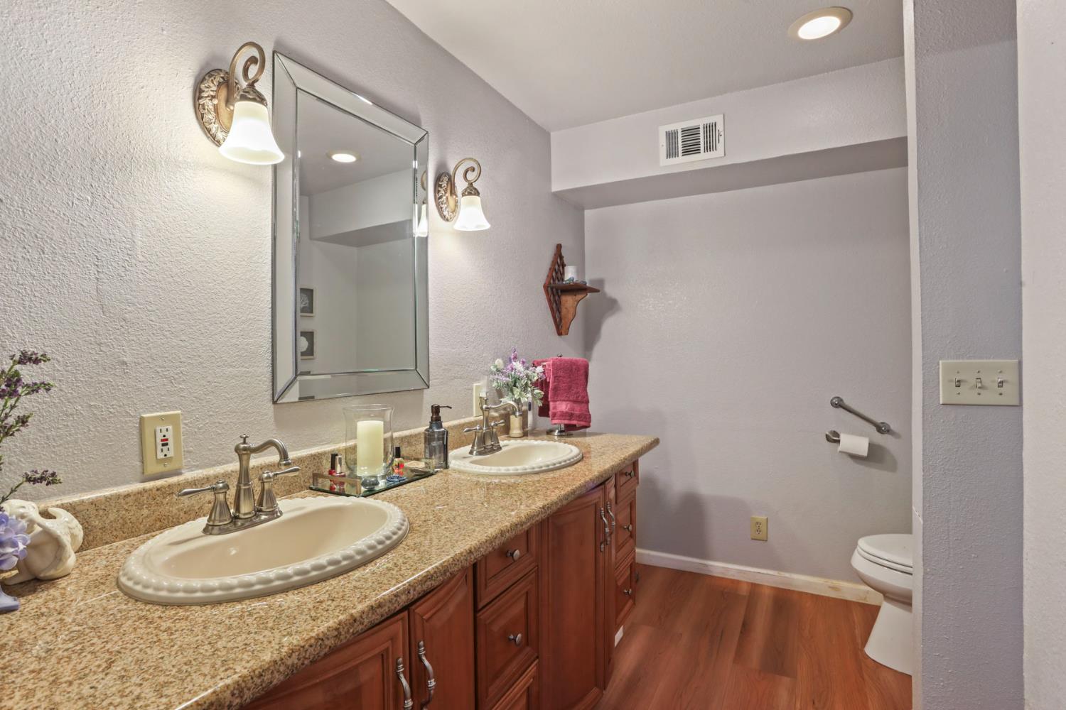 1601 Spring Court Tracy, CA 95376 - Photo 28 of 49 a bathroom with a granite countertop sink a mirror and a toilet