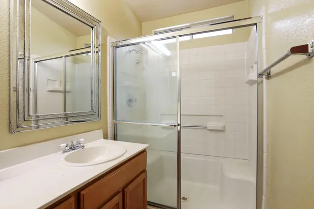 a bathroom with a shower sink vanity and mirror