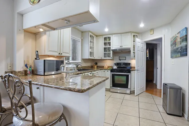 a kitchen with stainless steel appliances granite countertop a stove top oven a sink a dining table and chairs