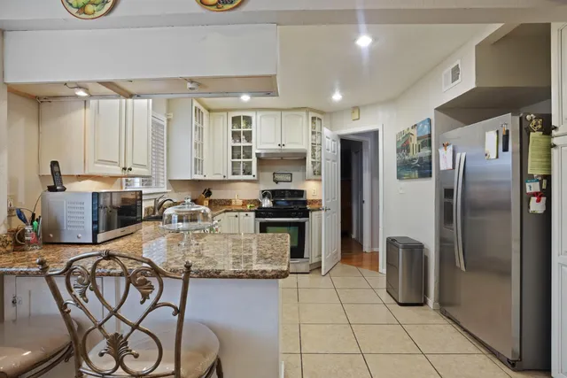 a kitchen with stainless steel appliances granite countertop a refrigerator and a stove top oven