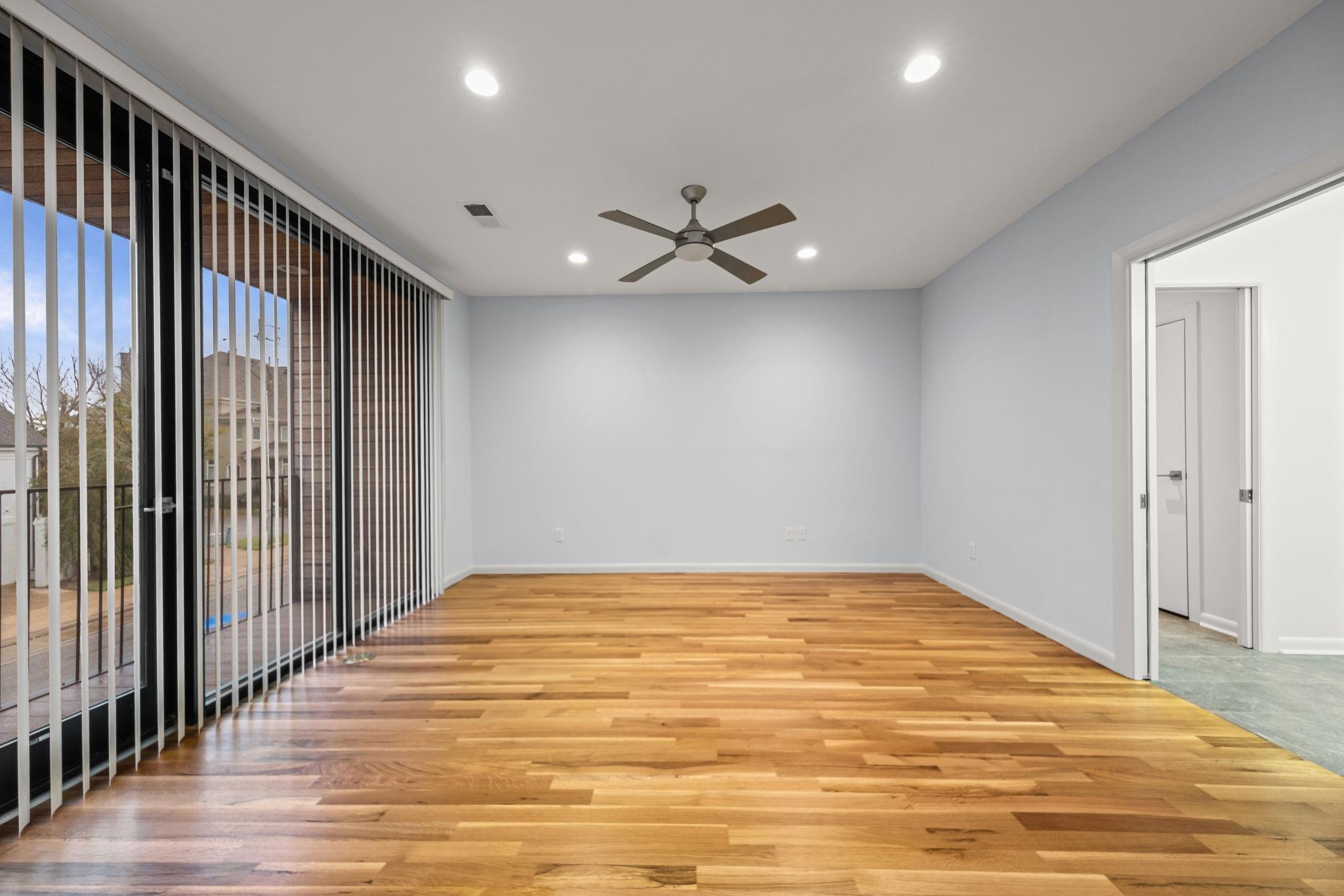 448 Tennessee Street Memphis, TN 38103 - Photo 25 of 39 Spacious room featuring wood-finish flooring, light blue walls, and a large sliding glass door with vertical blinds