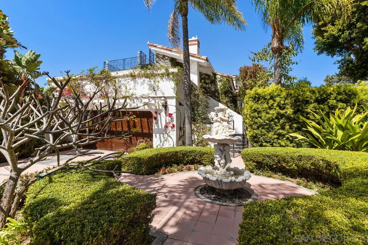 a front view of a multi story residential apartment building with yard and mountain in background