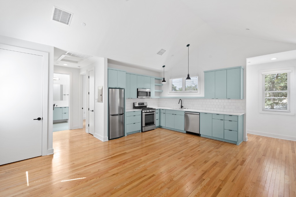 4006 Avenue C, Unit D Austin, TX 78751 - Photo 1 of 14 Kitchen featuring light wood-type flooring, light countertops, open shelves, pendant lighting, and stainless steel appliances