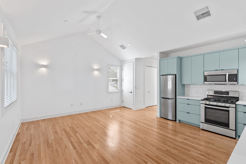 4006 Avenue C, Unit D Austin, TX 78751 - Photo 3 of 14 Kitchen featuring light countertops, appliances with stainless steel finishes, blue cabinets, backsplash, and light wood-style floors