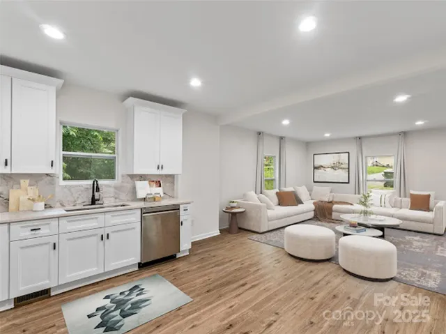 a large room with lots of white furniture and wooden floor