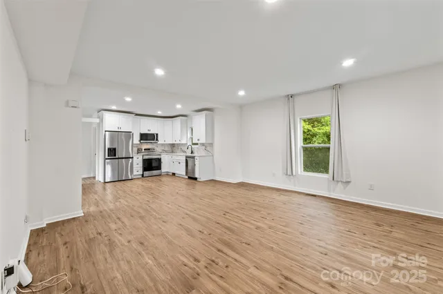 a view of a kitchen with a fridge and wooden floor