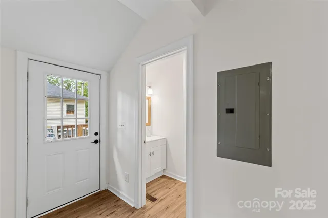 a view of a hallway with wooden floor and a bathroom