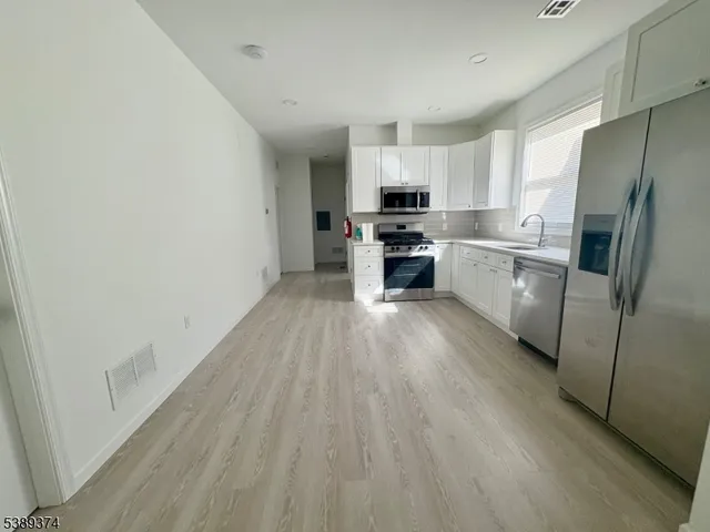 a kitchen with a refrigerator a stove top oven and white cabinets