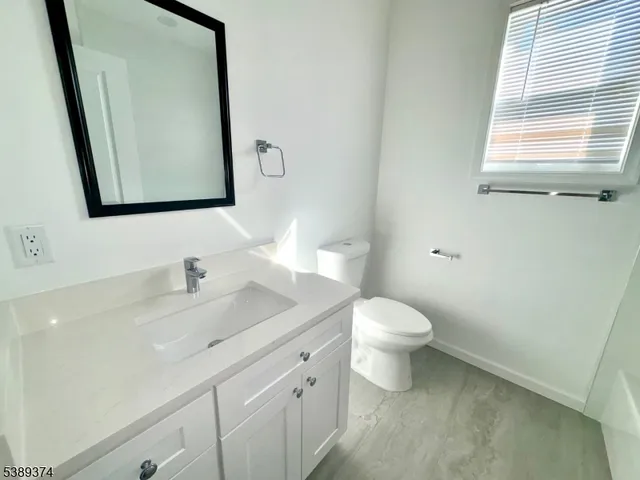 a bathroom with a granite countertop sink toilet and mirror