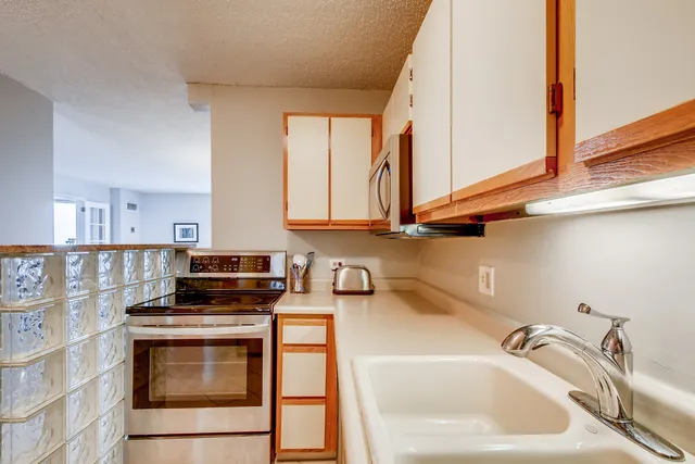 a kitchen with stainless steel appliances granite countertop a sink a stove and a microwave oven with white cabinets