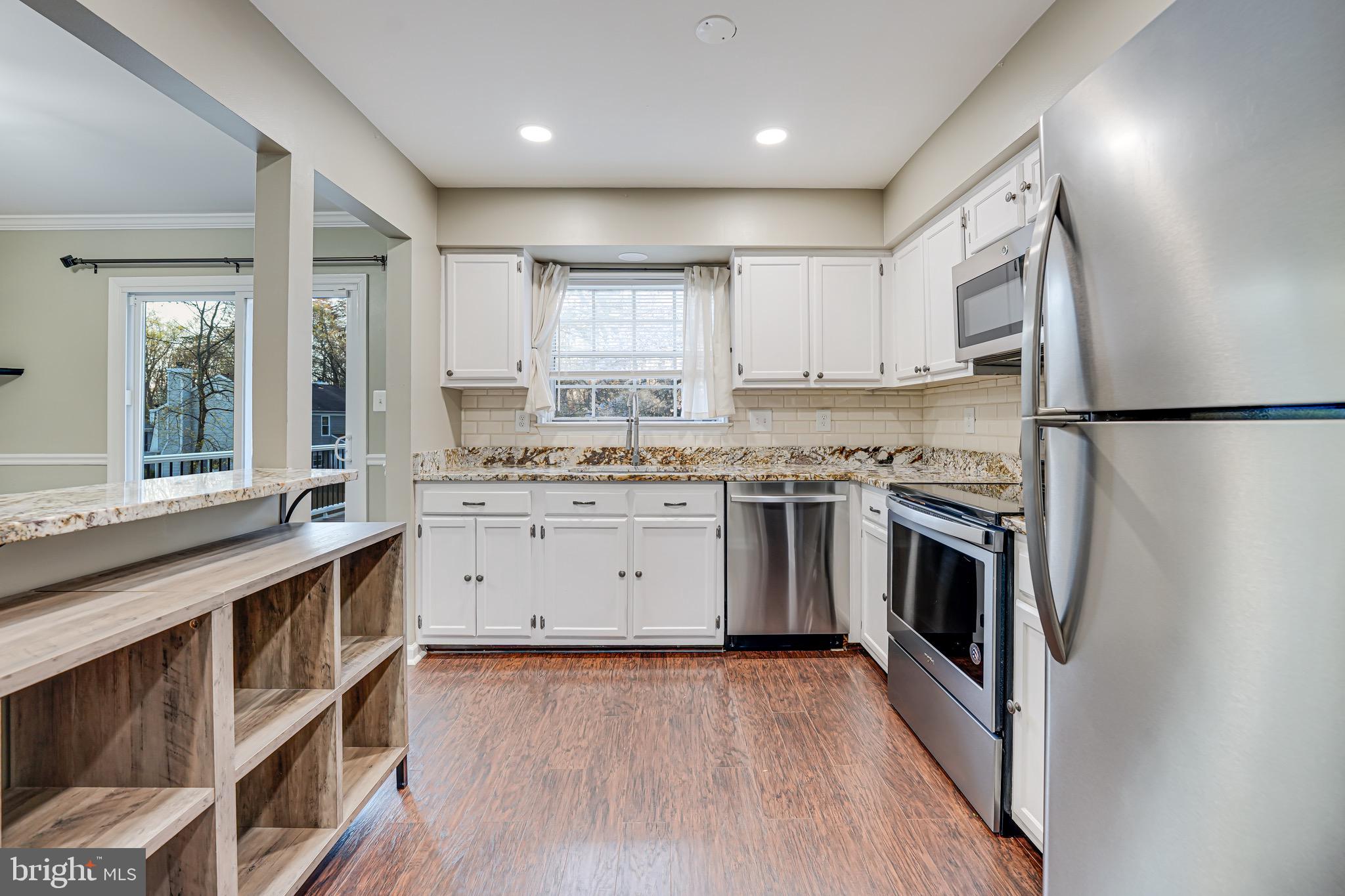15592 Northgate Drive Dumfries, VA 22025 - Photo 4 of 51 a kitchen with white cabinets stainless steel appliances and wooden floor